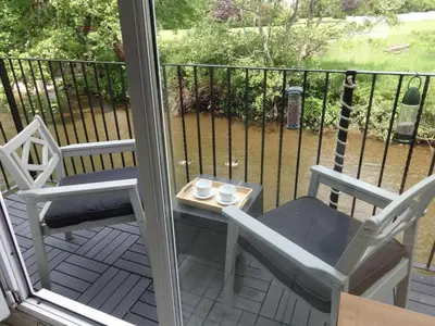 a balcony with two chairs and a table with cups on it at Riverbank Cottage River Ehan Double Balcony in Egremont