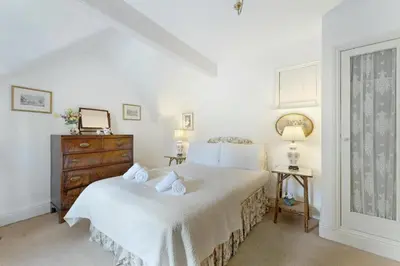 a white bedroom with a bed and a dresser at Poet's View Cottage in Grasmere