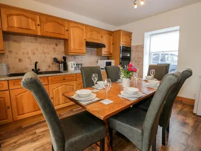 a kitchen with a wooden dining table and chairs at 2Loos in Newton Stewart