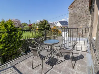 a patio with a table and chairs on a balcony at 2Loos in Newton Stewart