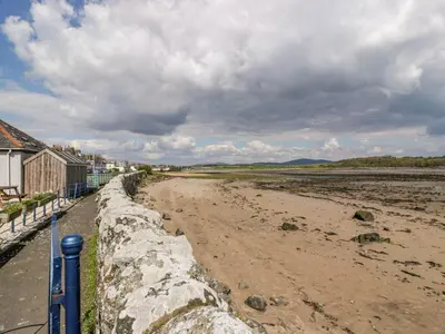 a beach with a retaining wall and a dirt road at 2Loos in Newton Stewart