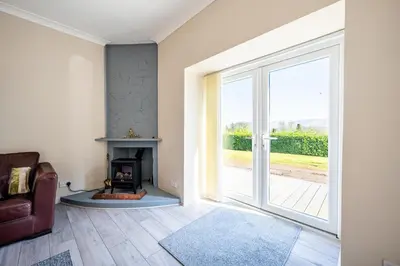 a living room with a fireplace and a sliding glass door at The Stables Cottage, Beattock, Moffat in Beattock