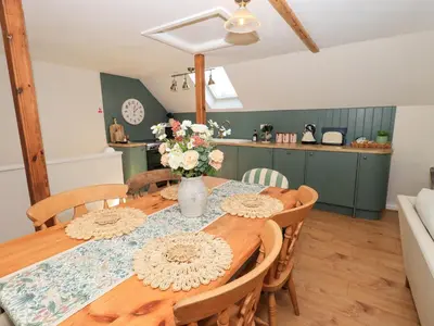 a dining room table with a vase of flowers on it at Corner Cottage in Penrith