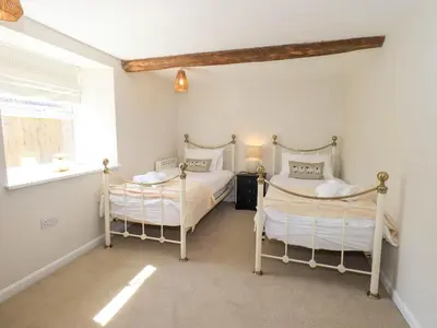 a bedroom with two beds and a window at Corner Cottage in Penrith