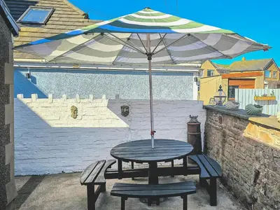 a picnic table with an umbrella and two benches at The St Bees Knees in St Bees