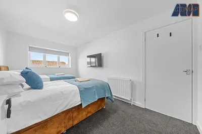 a white bedroom with a large bed with blue pillows at 3BR Home in Kilmarnock Sleeps 6 in Kilmarnock