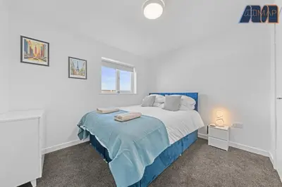 a bedroom with a blue and white bed and a window at 3BR Home in Kilmarnock Sleeps 6 in Kilmarnock