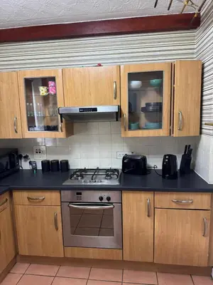 a kitchen with wooden cabinets and a stove top oven at Chic & Cozy 2BR Semi-Detached in Kilmarnock