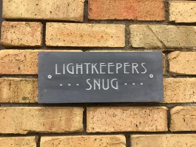 a sign on the side of a brick wall at Lightkeepers Snug in Portpatrick