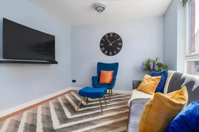 a living room with a couch and a clock on the wall at The Cozy Atmosphere Lodge in Moffat