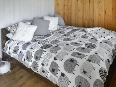 a bed with a black and white comforter with a laptop on it at The Shepherd's Rest in Auchencairn