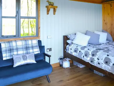 a bedroom with a bed and a blue chair at The Shepherd's Rest in Auchencairn