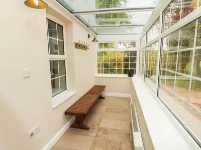a conservatory with a bench in a room with windows at Kirkland Howe Cottage in Frizington