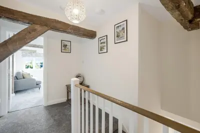 a staircase in a house with white walls and a chandelier at Beautiful 3 bedroom cottage close to Goodwood ! in Moffat