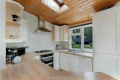 a kitchen with white cabinets and a wooden ceiling at Troutbeck Lodge in Bassenthwaite