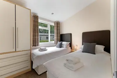 a bedroom with two beds and a window at Troutbeck Lodge in Bassenthwaite