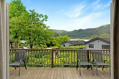 two chairs sitting on a porch with a fence at Troutbeck Lodge in Bassenthwaite