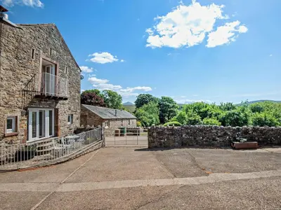 an old stone building with a fence and trees at 2 Bed in Ireby 96088 in Ireby