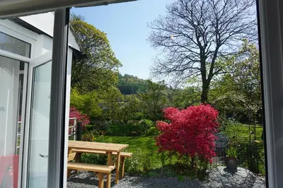 a window view of a garden with a bench outside at Lake View Country House and Self-catering Apartments in Grasmere