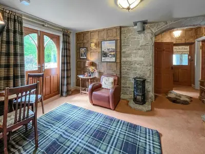 a living room with a stone fireplace and a chair at Upper Double Lodge in Kirkcudbright