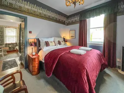 a bedroom with a large bed with a red blanket at Upper Double Lodge in Kirkcudbright