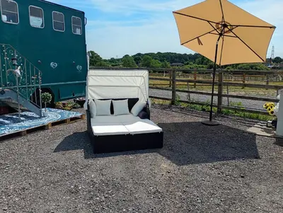a white couch sitting under an umbrella next to a train at The Box in Moffat