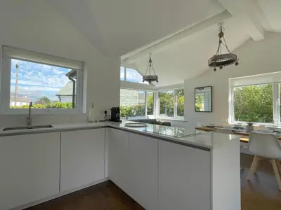 a white kitchen with white cabinets and windows at Mill House in Braithwaite