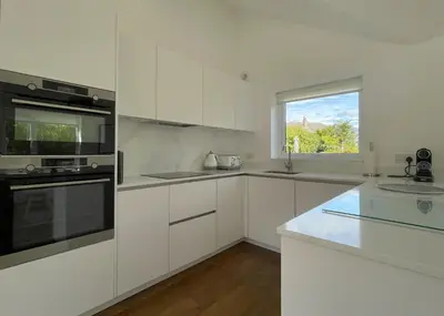 a white kitchen with white cabinets and a window at Mill House in Braithwaite