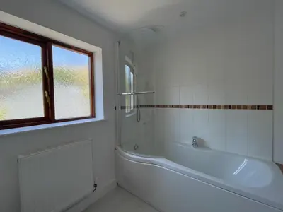 a white bathroom with a tub and a window at Mill House in Braithwaite