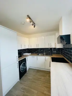 a kitchen with white cabinets and a washing machine at Bow Church in Moffat