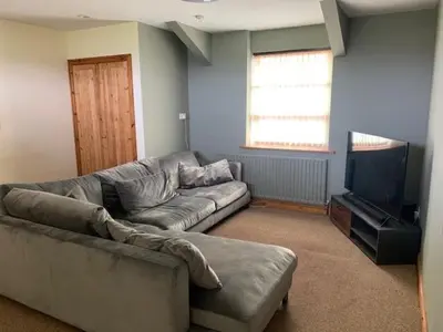 a living room with a couch and a flat screen tv at Unique schoolhouse in the peaceful Western Lakes in Bootle