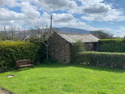 a bench sitting in the yard of a house at Unique schoolhouse in the peaceful Western Lakes in Bootle