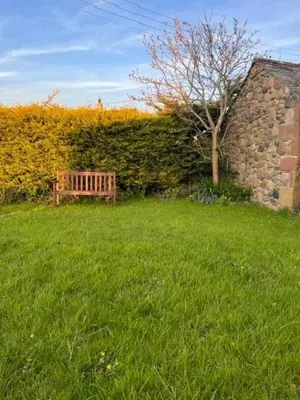 a wooden bench sitting in a field of grass at Unique schoolhouse in the peaceful Western Lakes in Bootle