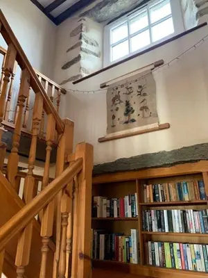 a room with a staircase and bookshelves with books at Unique schoolhouse in the peaceful Western Lakes in Bootle