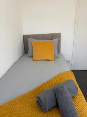 a bed with a yellow blanket and a yellow pillow at Modern 3BR House Near Manchester-Parking Included in Moffat