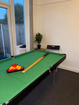 a green pool table with two cuesticks on it at Modern 3BR House Near Manchester-Parking Included in Moffat
