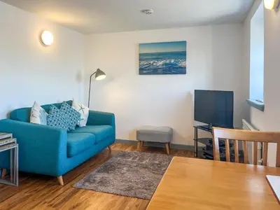 a living room with a blue couch and a tv at Ninians Landing in Kirkcudbright