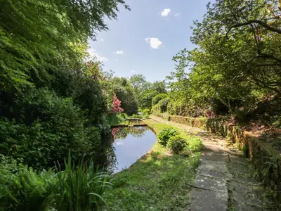 a small pond in a garden with trees at Nithbank Cottage in Thornhill