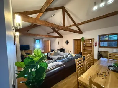 a living room with a couch and a table at Old Corner Barn Lake District Escape by PolkaStays in Penrith