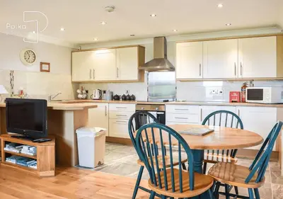 a kitchen with a table and chairs and a television at Crag Barn Cottage Lake District by PolkaStays in Penrith