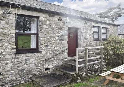 a stone house with a red door and a wooden porch at Crag Barn Cottage Lake District by PolkaStays in Penrith