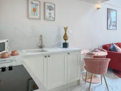 a white kitchen with a sink and a table at Three Chapel Court in Cockermouth