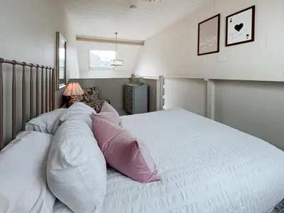 a bedroom with a large bed with pink and white pillows at Three Chapel Court in Cockermouth