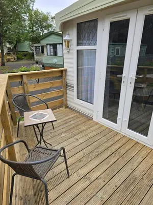 a patio with two chairs and a table on a deck at Woodlands Retreat Holiday Home in Ballantrae