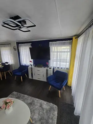a living room with two blue chairs and a table at Woodlands Retreat Holiday Home in Ballantrae