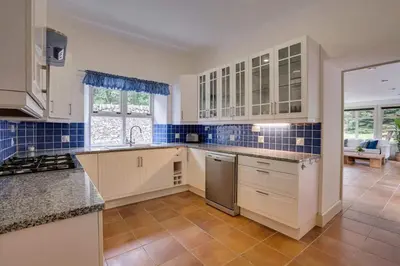 a large kitchen with white cabinets and blue tiles at Mid Lodge, Penninghame Estate in Challoch