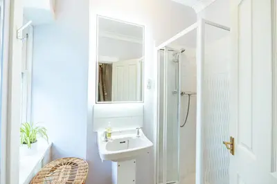 a white bathroom with a sink and a shower at Penninghame Estate - West Lodge in Challoch