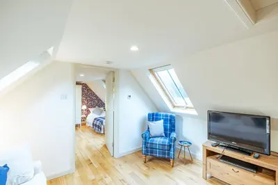a living room with a tv and a blue chair at Penninghame Estate - West Lodge in Challoch
