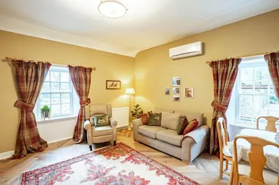 a living room with a couch and a chair at Penninghame Estate- Gardeners Cottage in Challoch