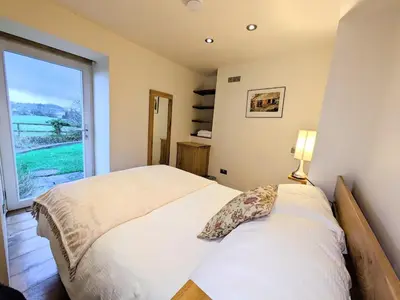 a bedroom with a bed and a large window at The Coach House at Durhamhill with llamas & games room mini cinema in Kirkpatrick Durham